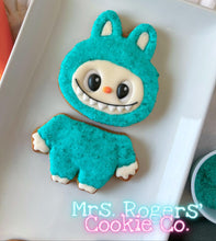 Load image into Gallery viewer, Cookie in a teal costume with a face on a white plate, branded &#39;Mrs. Rogers&#39; Cookie Co&#39;.

